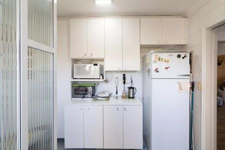 Apartamento à venda com 77m², 3 quartos e 1 vagaCozinha com geladeira, fogão e micro-ondas, com iluminação adequada e mobiliário simples.