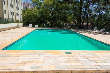 Apartamento à venda com 77m², 3 quartos e 1 vagaPiscina com chão de pedra e cadeiras brancas ao redor.