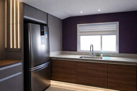 Casa à venda com 131m², 2 quartos e 1 vagaCozinha moderna com geladeira, pia e armários de madeira, iluminada por luzes de LED.