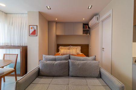 Apartamento à venda com 28m², 1 quarto e sem vagaCama simples com colchão e travesseiro, com uma pequena mesa e cadeira ao lado, e uma porta ao fundo.