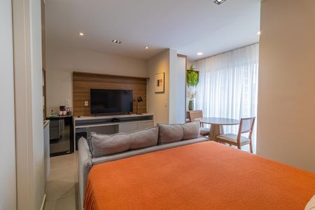 Apartamento à venda com 28m², 1 quarto e sem vagaQuarto com cama, sofá, TV e cozinha pequena, com janela grande e iluminação boa.