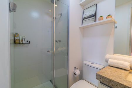 Apartamento à venda com 28m², 1 quarto e sem vagaBanheiro com chuveiro e pia branca, com prateleiras de produtos de higiene e decoração simples.