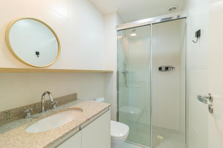 Apartamento à venda com 69m², 2 quartos e 1 vagaBanheiro com piso de porcelanato, pia e vaso sanitário brancos, e espelho redondo com moldura dourada.