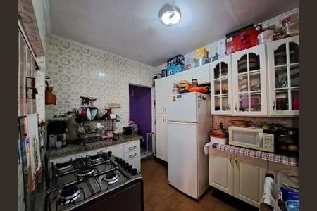 Casa à venda com 173m², 3 quartos e 2 vagasCozinha com geladeira, fogão e microondas, com móveis brancos e azulejos brancos com desenho de flores.