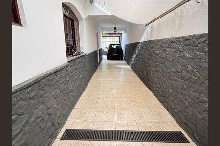 Casa à venda com 170m², 4 quartos e 5 vagasPátio com garagem e entrada para casa, com piso de cerâmica e parede de pedra.