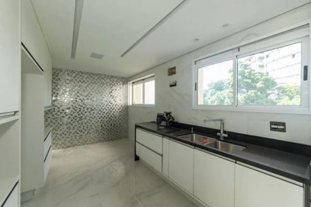 Apartamento à venda com 205m², 4 quartos e 4 vagasCozinha moderna com móveis brancos e piso de porcelanato, iluminada por luz natural e com vista para a floresta.
