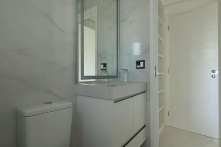 Apartamento à venda com 205m², 4 quartos e 4 vagasBanheiro com piso de porcelanato, pia e espelho em madeira, com iluminação adequada e mobiliário simples.