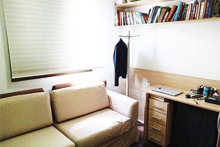 Apartamento à venda com 92m², 3 quartos e 2 vagasSala com sofá, mesa e estante de livros, iluminada por luz natural.