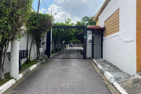 Casa à venda com 130m², 2 quartos e 4 vagasPorta de entrada de um condomínio com uma pessoa caminhando pela rua.