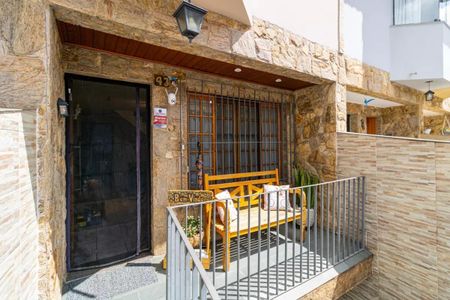 Casa à venda com 130m², 2 quartos e 4 vagasPorch with a yellow bench and a stone wall, with a black door and a white wall in the background.
