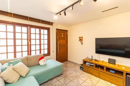 Sala com sofá, TV e porta de madeira, iluminada por lâmpadas de piso e com janelas de madeira com vidros quadrados. de casa à venda com 2 quartos, 130m² em Vila Medeiros, São Paulo
