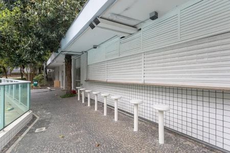 Apartamento à venda com 60m², 2 quartos e 2 vagasPavimentação de pedras e bancos de concreto em frente a uma construção branca.