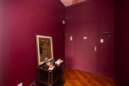 Apartamento à venda com 100m², 2 quartos e sem vagaParede com pintura vermelha e quadro de arte, com uma mesa de madeira e alguns objetos decorativos.