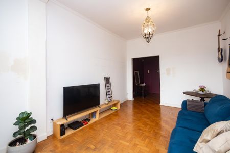 Apartamento à venda com 100m², 2 quartos e sem vagaSala com TV e sofá azul, com piso de madeira e iluminação adequada.