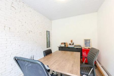Casa à venda com 168m², 3 quartos e 1 vagaSala de escritório com mesa e cadeiras, parede de tijolos brancos e iluminação natural.