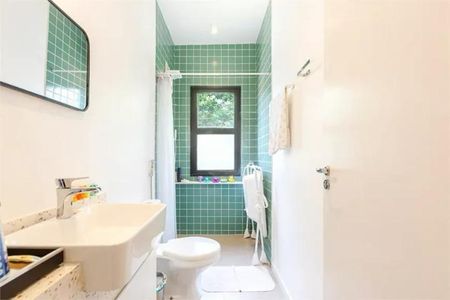 Casa à venda com 168m², 3 quartos e 1 vagaBanheiro com piso de azulejos, vaso sanitário e banheira, com janela e cortina branca.