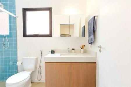 Casa à venda com 168m², 3 quartos e 1 vagaBanheiro com pia e vaso sanitário brancos, armário de madeira e espelho acima do pia.