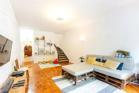 Casa à venda com 168m², 3 quartos e 1 vagaSala com sofá, TV e mesa de madeira, com uma escada no fundo e uma parede branca.