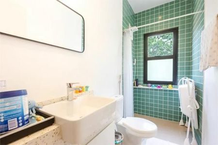 Casa à venda com 168m², 3 quartos e 1 vagaBanheiro com piso de azulejos, vaso sanitário e pia branca, com uma janela com cortina branca e uma porta de acesso.