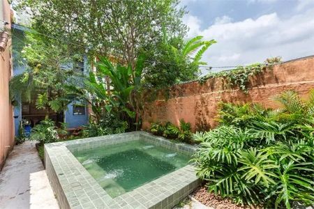 Casa à venda com 168m², 3 quartos e 1 vagaPiscina com teto de madeira e paredes de tijolos, cercada por plantas e árvores.