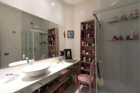 Casa à venda com 147m², 3 quartos e 2 vagasBanheiro com pia e espelho grande, com prateleiras de produtos de higiene e decoração.