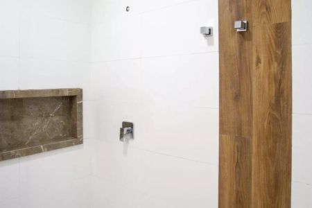 Casa à venda com 183m², 3 quartos e 4 vagasBanheiro com piso de porcelanato e parede branca, com uma bancada de mármore e dois chuveiros de cabeça.