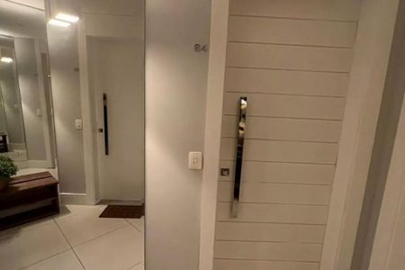 Apartamento à venda com 125m², 3 quartos e 2 vagasParede branca com porta de madeira e espelho grande, iluminada por lâmpadas brancas.