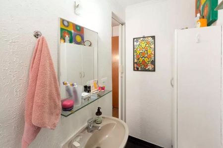Apartamento à venda com 85m², 2 quartos e sem vagaBanheiro com pia, espelho e toalha, com decoração colorida e pintura branca.