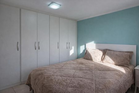 Apartamento à venda com 72m², 3 quartos e 2 vagasQuarto com cama de casal e armários de madeira, iluminado por uma lâmpada de teto.