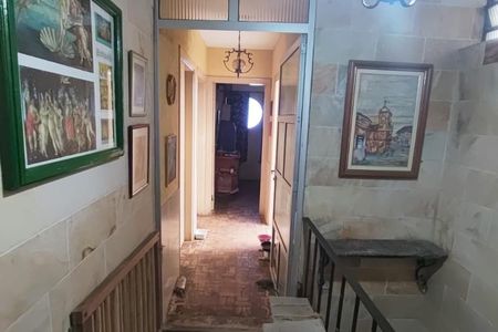 Casa à venda com 260m², 4 quartos e 3 vagasParede com quadros e escada de madeira, com uma porta aberta para uma sala com um sofá e uma mesa de centro.