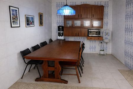 Casa à venda com 260m², 4 quartos e 3 vagasComedor com mesa de madeira e cadeiras pretas, com iluminação azul e decoração de pinturas na parede.