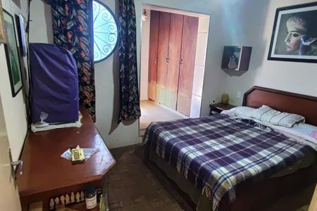 Casa à venda com 260m², 4 quartos e 3 vagasQuarto com cama, mesa e TV, com uma porta para o corredor.