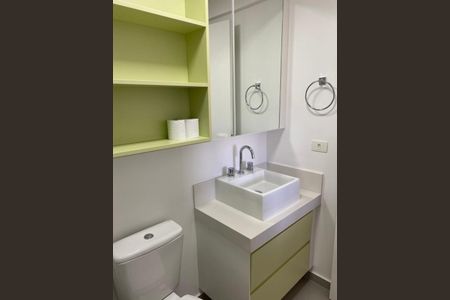 Banheiro com pia e vaso sanitário brancos, armário com espelho e prateleiras verde-claro. de apartamento à venda com 2 quartos, 82m² em Bosque da Saúde, São Paulo