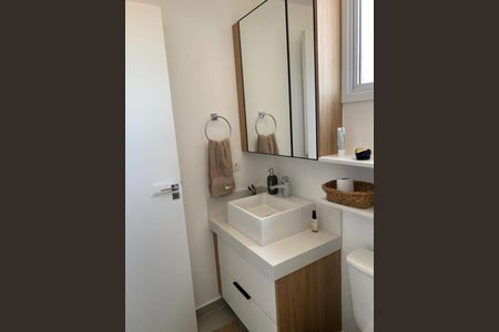 Banheiro com pia e vaso sanitário branco, com gavetas e armários de madeira, e espelho acima do pia. de apartamento à venda com 2 quartos, 82m² em Bosque da Saúde, São Paulo