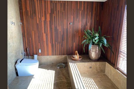 Apartamento à venda com 466m², 4 quartos e 6 vagasBanheiro com piso de porcelanato, parede em madeira e vaso de planta.