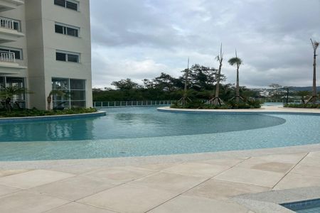 Apartamento à venda com 55m², 2 quartos e 1 vagaPiscina com vista para o mar e edifício de apartamentos ao fundo.