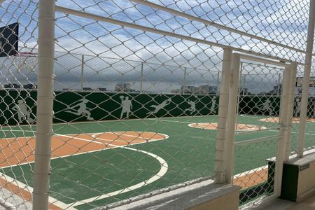 Apartamento à venda com 55m², 2 quartos e 1 vagaCorte de uma quadra de basquete com vista para o mar, com uma grade de segurança branca e uma parede verde com silhuetas de esportistas.