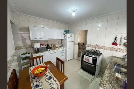 Casa à venda com 200m², 4 quartos e 2 vagasCozinha com móveis brancos, geladeira, fogão e mesa com frutas.