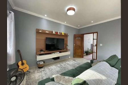 Casa à venda com 200m², 4 quartos e 2 vagasSala com TV e sofá, com uma guitarra ao lado e uma porta de entrada ao fundo.
