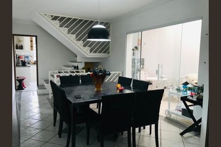 Casa à venda com 170m², 3 quartos e 5 vagasComida e bebida em uma mesa de madeira com cadeiras pretas, com uma escada branca no fundo e uma porta de vidro na direita.