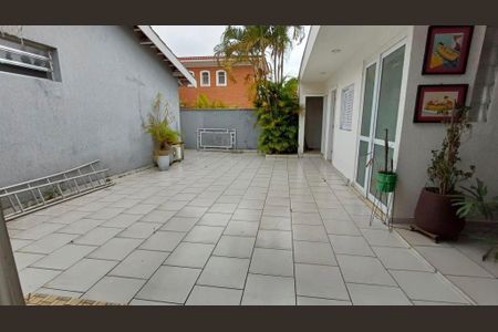 Casa à venda com 340m², 4 quartos e 4 vagasPátio com piso de azulejos, plantas e uma vista para a casa ao fundo.