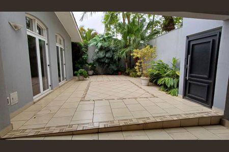 Casa à venda com 340m², 4 quartos e 4 vagasPátio com piso de azulejos e plantas ao redor, com uma porta de entrada preta e uma parede de concreto.