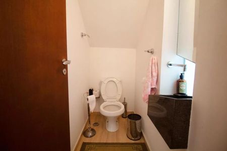 Casa à venda com 400m², 4 quartos e 6 vagasBanheiro com piso de madeira, vaso sanitário e lavatório, com toalha e sabonete de banho.