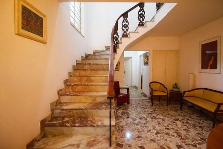 Casa à venda com 400m², 4 quartos e 6 vagasEscada em mármore com balcão de madeira e pintura branca no fundo.