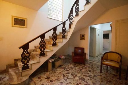 Casa à venda com 400m², 4 quartos e 6 vagasEscada em curva com balaustrada de madeira e piso de azulejos em um ambiente iluminado por janelas grandes.