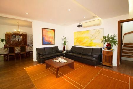 Casa à venda com 400m², 4 quartos e 6 vagasSala com móveis de couro, pinturas e uma mesa de centro com objetos decorativos.