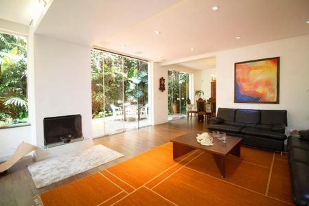 Casa à venda com 400m², 4 quartos e 6 vagasSala com decoração moderna e vista para o jardim, com uma lareira e uma mesa de jantar.