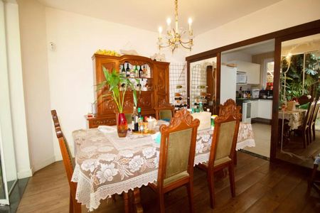 Casa à venda com 400m², 4 quartos e 6 vagasComedor com mesa de madeira e cadeiras, com um aparador de madeira atrás da mesa.