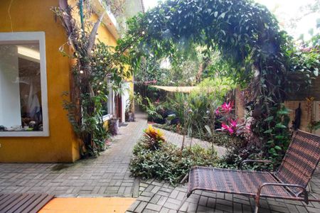 Casa à venda com 400m², 4 quartos e 6 vagasPátio com jardim e cadeira de balanço, com vista para a casa amarela.