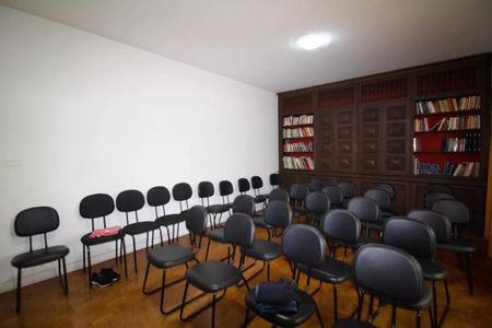 Casa à venda com 400m², 4 quartos e 6 vagasSala com móveis de madeira e prateleiras de livros, iluminada por uma lâmpada de teto.
